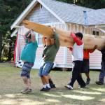 Tribal members carry a newly carved canoe to the shore of Lake Crescent on Thursday at the NatureBridge Campus. (Emily Hanson/Peninsula Daily News)