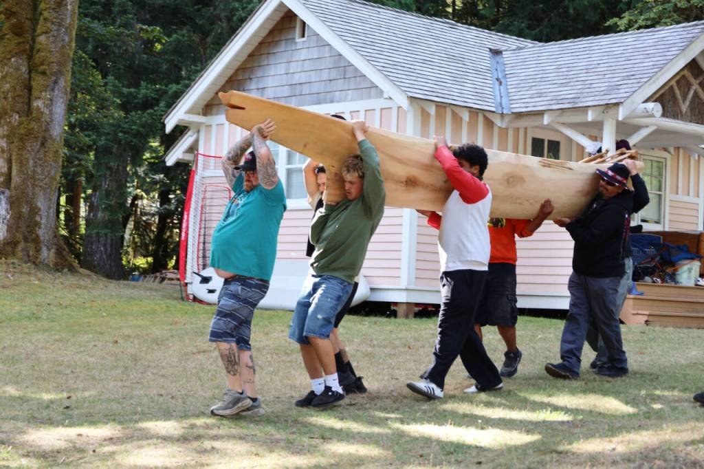 Tribal members carry a newly carved canoe to the shore of Lake Crescent on Thursday at the NatureBridge Campus. (Emily Hanson/Peninsula Daily News)