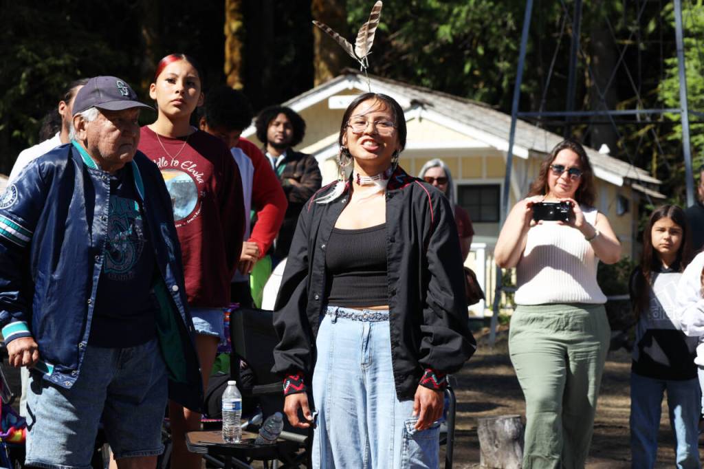 Cheyenne Wheeler announces the name her grandfather, Frank Charles, left, chose for one of the canoes Thursday at the NatureBridge Campus. (Emily Hanson/Peninsula Daily News)