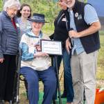 Tom Sanford, executive director of North Olympic Land Trust, presents Janice Hunt, the youngest granddaughter of William Dick, who purchased the property and built the Big Red Barn Farm 1904, with the Farmer of the Year award on July 26. (Monica Berkseth/for Olympic Peninsula News Group)