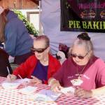 Judges Marylan Thayer and Roxanne Olsen taste entries to the Wild Blackberry Pie Baking contest while Julie Helgeson, the contest coordinator, prepares the next sample behind them. (Dave Logan/for Peninsula Daily News)