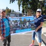 Lincoln Erickson, director of construction for Habitat for Humanity of Clallam County, left, and CEO Colleen Robinson hold up a placard on Friday with the before photos of the property the organization bought and built 25 percent of a house on during its first Blitz Build. (Emily Hanson/Peninsula Daily News)