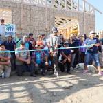 Habitat for Humanity of Clallam County site lead Sawyer Schoenrock, with scissors, cuts the ribbon for the organizations build on Friday at 1127 W. Hazel St. (Emily Hanson/Peninsula Daily News)